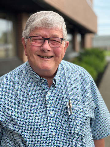 Doctor with blue shirt, gray hair and nice black glasses