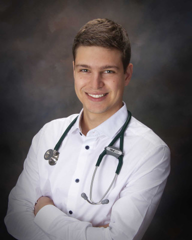 Young doctor smiles with stethoscope around his neck