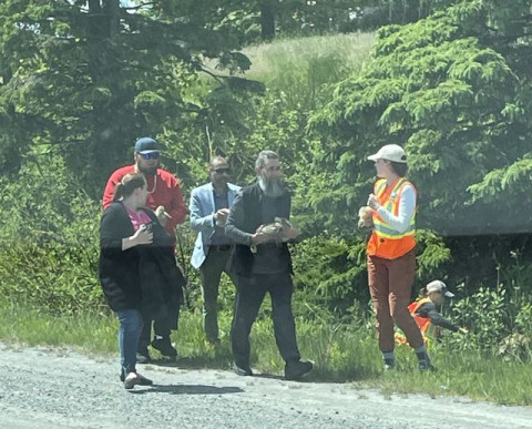 Group of individuals on roadside with a goose