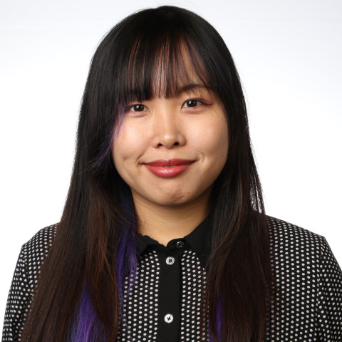 a woman with long brown hair, wearing a black and white poka dot shirt